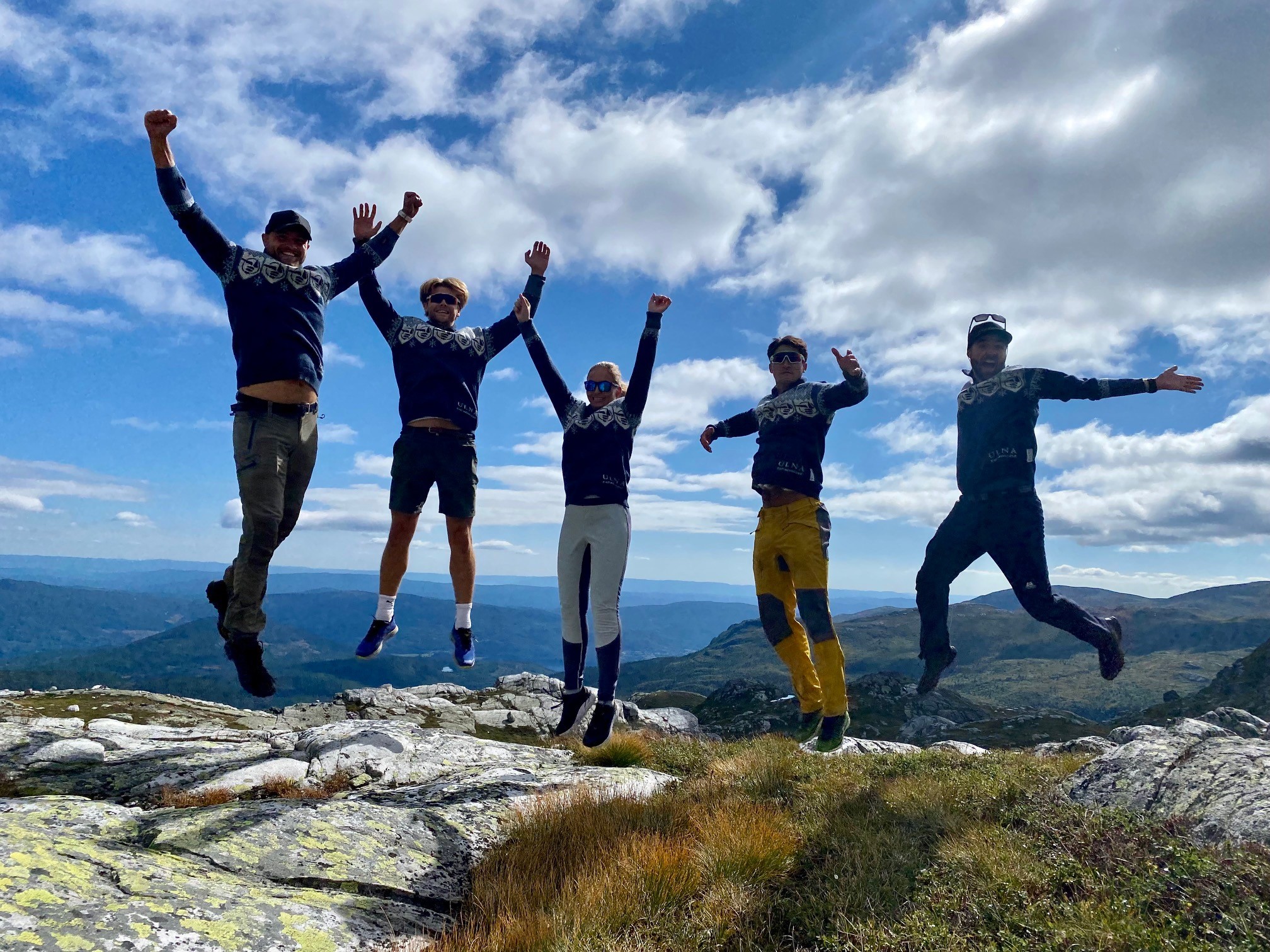 Gruppebilde av ansatte som hopper på et fjell